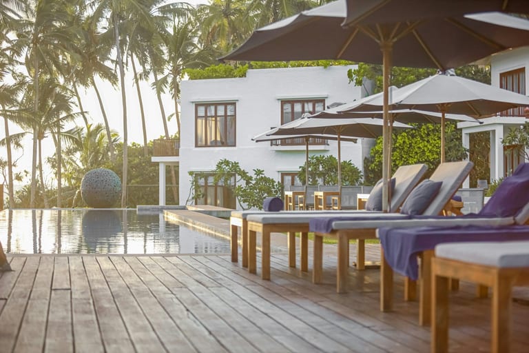 Resort pool terrace with wooden deck, loungers and umbrellas